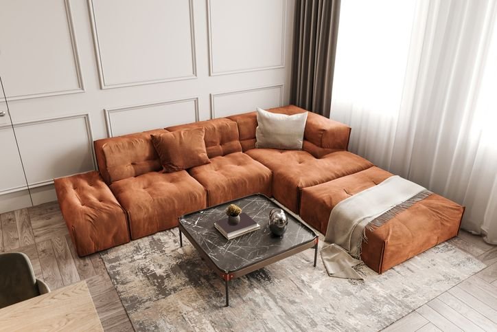 Sala de estar ampla com sofá modulado em formato L em tecido terracota, tapete claro e decoração contemporânea