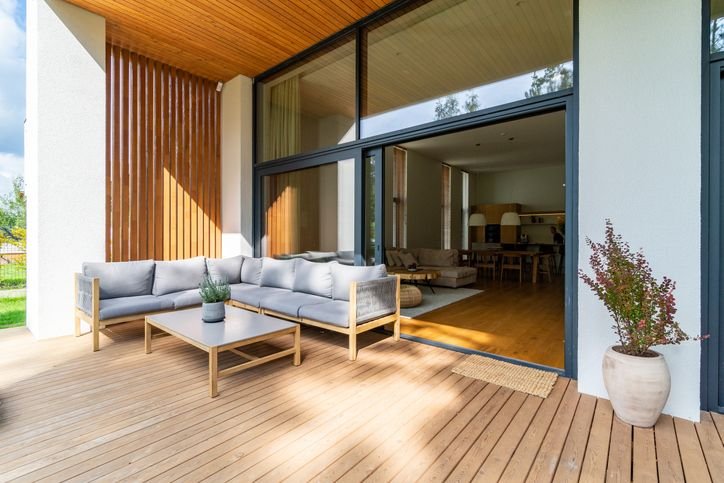 Sof&aacute; de madeira no ambiente externo de uma casa moderna com piso de madeira, ideal pra decora&ccedil;&atilde;o contempor&acirc;nea e conforto ao ar livre.