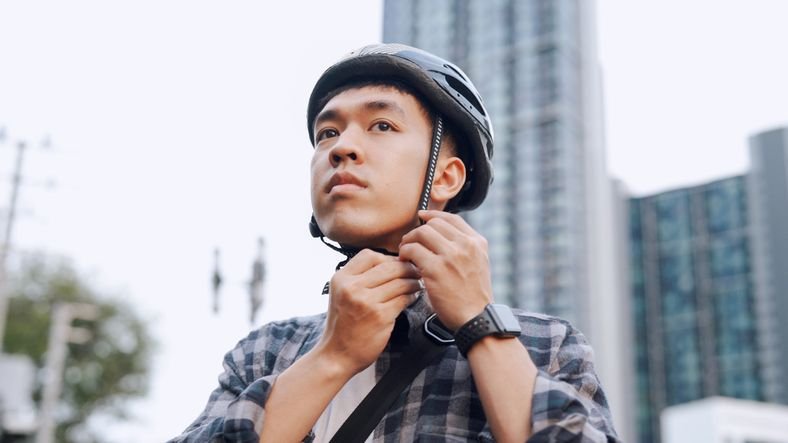 Homem ajustando o capacete de segurança antes de iniciar o trajeto com sua scooter elétrica, destacando a prevenção.