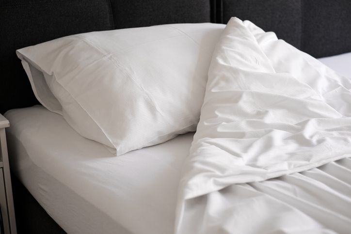 close numa cama com len&ccedil;ol branco