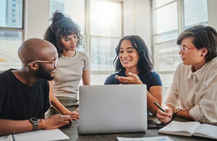 Grupo de pessoas discutindo em uma reuni&atilde;o de trabalho, ambiente de escrit&oacute;rio moderno, com foco em diversidade e colabora&ccedil;&atilde;o.