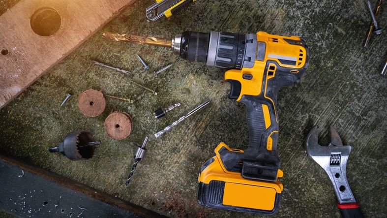 Parafusadeira DeWalt profissional, mostrando modelo a bateria com empunhadura ergonômica e design robusto, na bancada com acessórios como brocas.