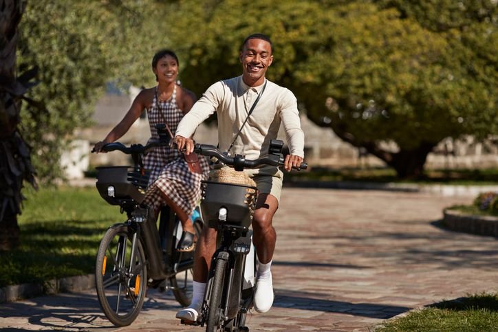 Dois jovens andando de bicicletas el&eacute;tricas em um parque.
