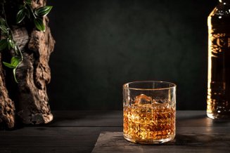 Copo de whisky com gelo sobre fundo escuro, em clima sofisticado para falar dos rótulos mais caros do mundo.