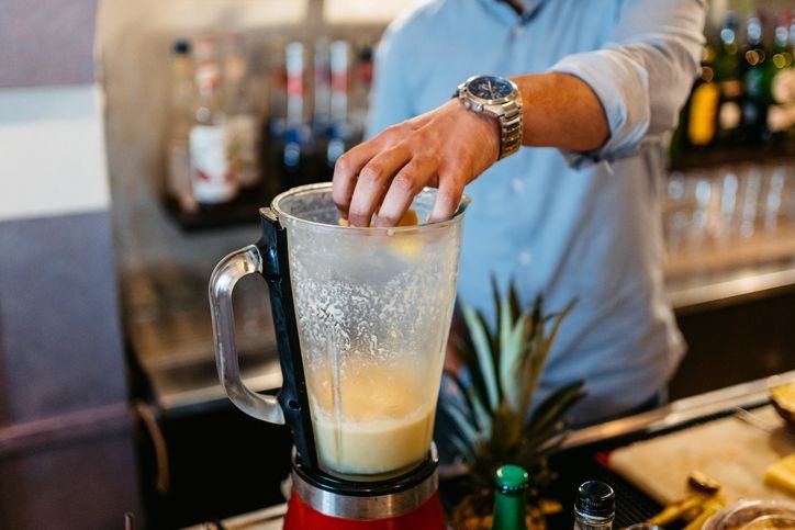 Liquidificador potente em funcionamento durante o preparo de uma bebida em um bar, destacando a for&ccedil;a e efici&ecirc;ncia do equipamento ao misturar os ingredientes rapidamente.