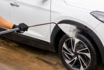 mão lavando pneu do carro com lavadora de alta pressão