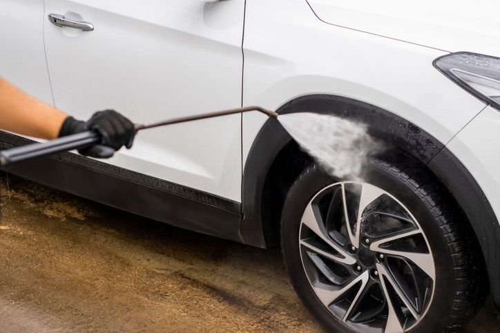 mão lavando pneu do carro com lavadora de alta pressão