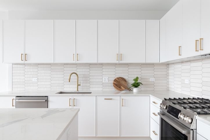 Cozinha com arm&aacute;rios brancos. Parede em azulejo e arm&aacute;rios de bancada e suspenso, todos na cor branca deixando a cozinha padronizada. 