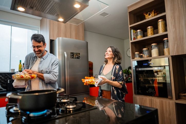 Casal preparando refei&ccedil;&atilde;o juntos em cozinha moderna.