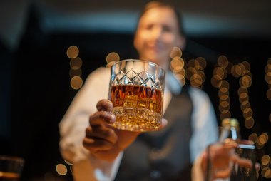 Bartender servindo whisky em copo baixo, cena que reforça a importância de verificar a procedência da bebida.