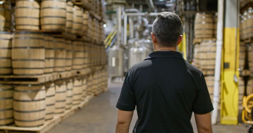 Trabalhador em destilaria acompanhando a produção do whisky, bebida feita com cereais fermentados e envelhecida em barris.