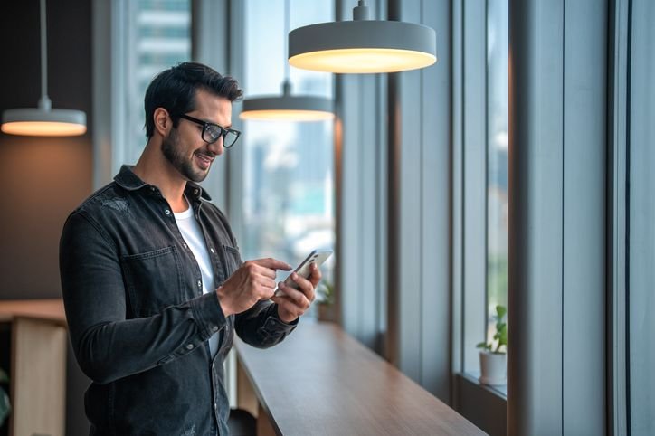 Homem de negócios usando smartphone Xiaomi 14T em escritório moderno e bem iluminado.