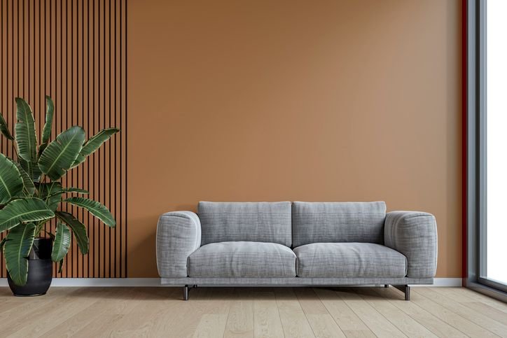 Sof&aacute; cinza numa sala de estar moderna, com parede ripada e planta decorativa.