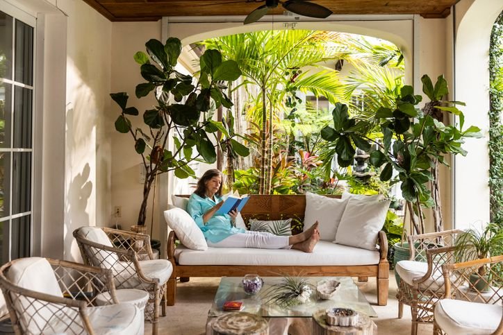 Sofá pra varanda em área externa coberta, com poltronas, mesa de centro e plantas ao redor, criando um ambiente aconchegante pra descanso.