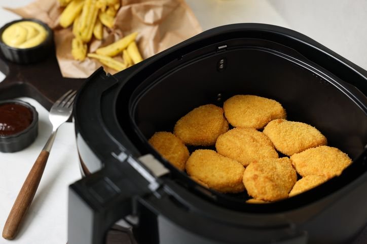 Nuggets crocantes sendo preparados em uma air fryer forno, representando a escolha de qual &eacute; a melhor air fryer pra cozinhar. 