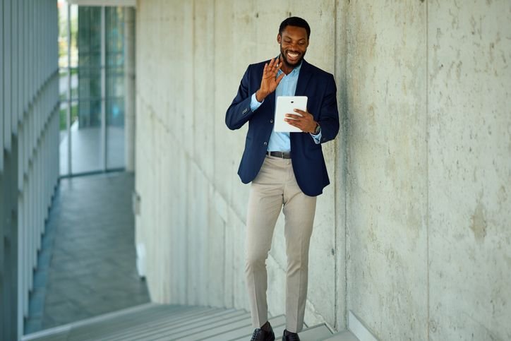 Homem  com terno azul sorrindo e usando um tablet