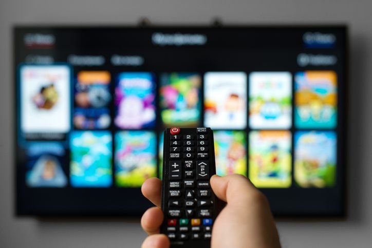 uma mão com controle remoto apontando para uma tv full hd