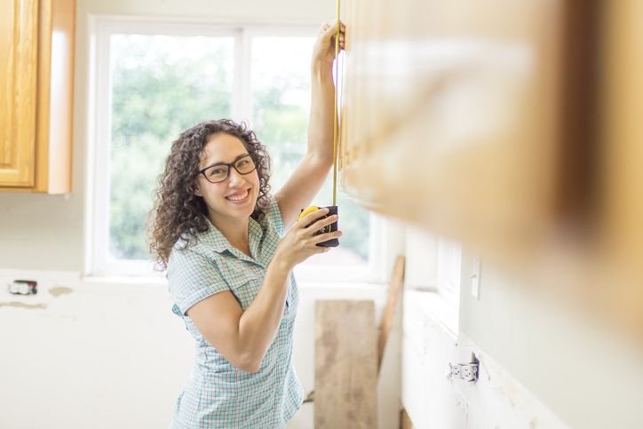 Mulher medindo armário de cozinha com trena para instalar micro-ondas no nicho
