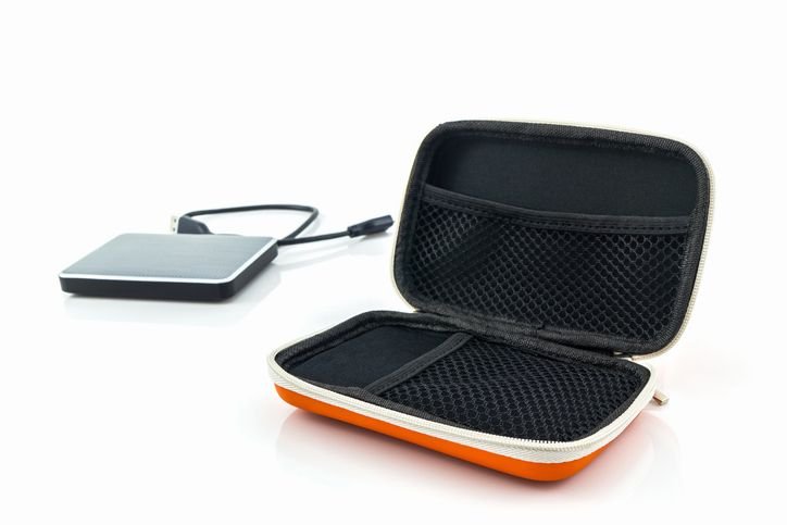 HD externo conectado a um fio. Em primeiro plano uma case para proteção do HD.