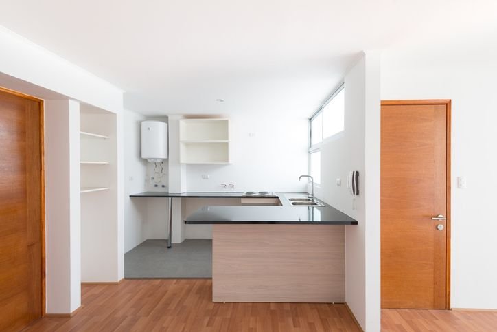 Cozinha simples com balc&atilde;o, pia e bancada de pedra.