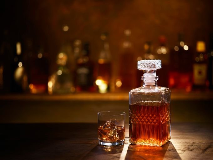 Garrafa e copo de bourbon sobre balcão de bar, em cena para comparar a diferença entre whisky e bourbon.