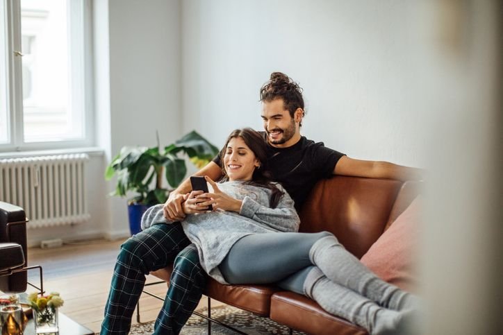 Casal jovem relaxando no sofá enquanto usa smartphone Poco F7 juntos.